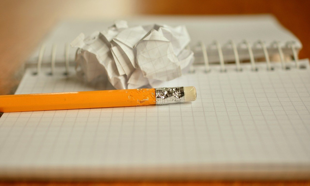 A chewed up pencil lying on an empty notebook.