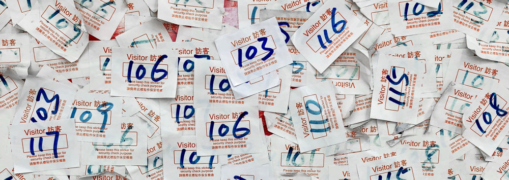 A pile of visitor passes, each with a number on them.